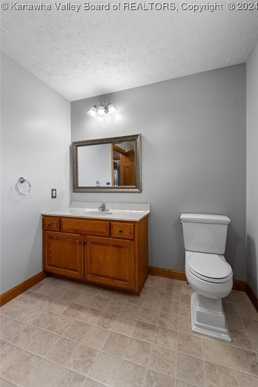 bathroom featuring a textured ceiling, vanity, toilet, and a chandelier