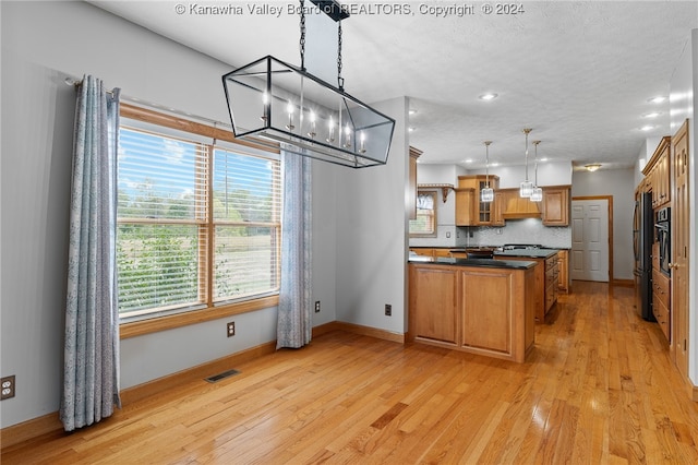 kitchen featuring pendant lighting, appliances with stainless steel finishes, light hardwood / wood-style flooring, and backsplash