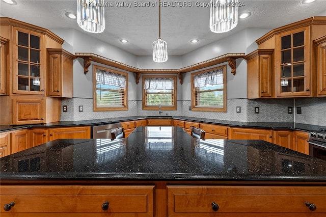 kitchen with a textured ceiling, sink, a notable chandelier, hanging light fixtures, and stainless steel dishwasher