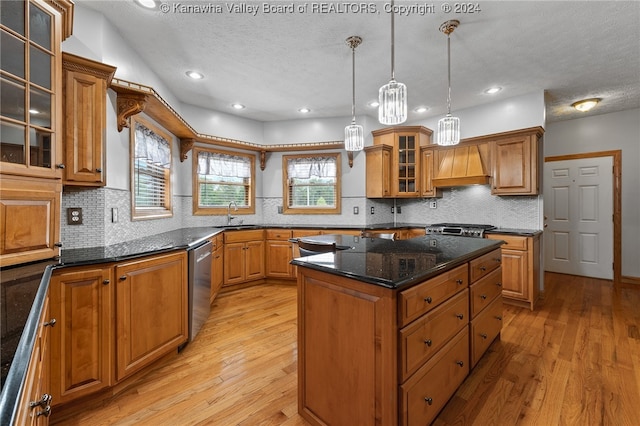 kitchen with pendant lighting, light wood-type flooring, custom range hood, a kitchen island, and decorative backsplash