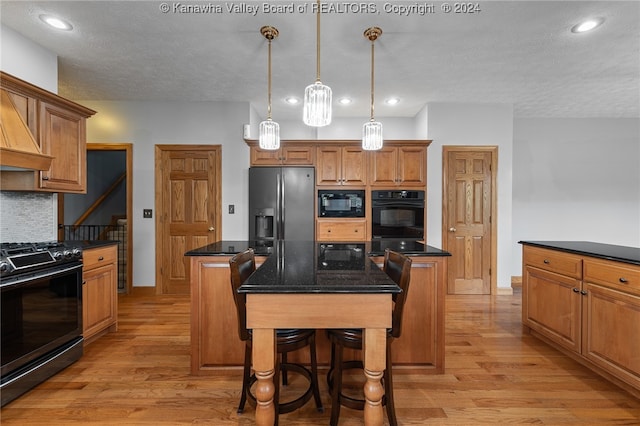 kitchen featuring pendant lighting, a kitchen island, backsplash, black appliances, and light wood-type flooring