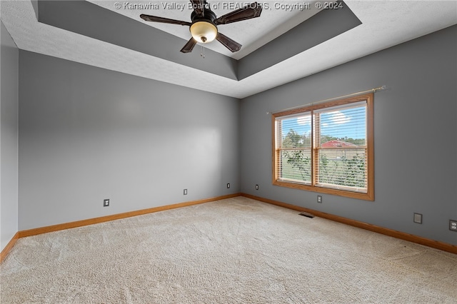 carpeted empty room featuring ceiling fan, a textured ceiling, and a tray ceiling