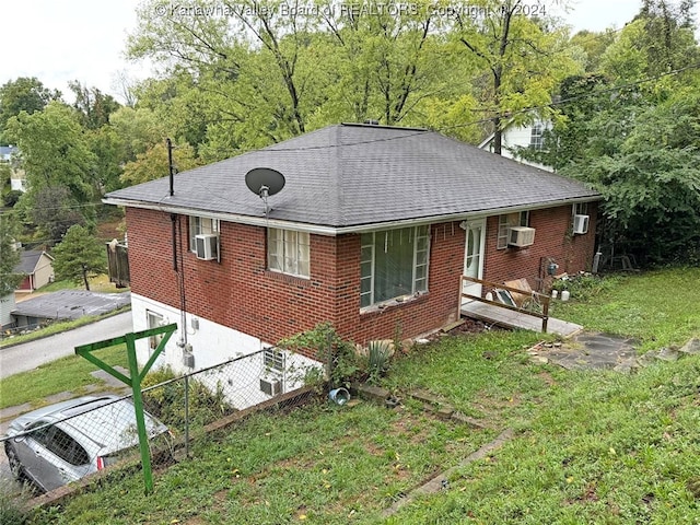 exterior space featuring a lawn and an AC wall unit