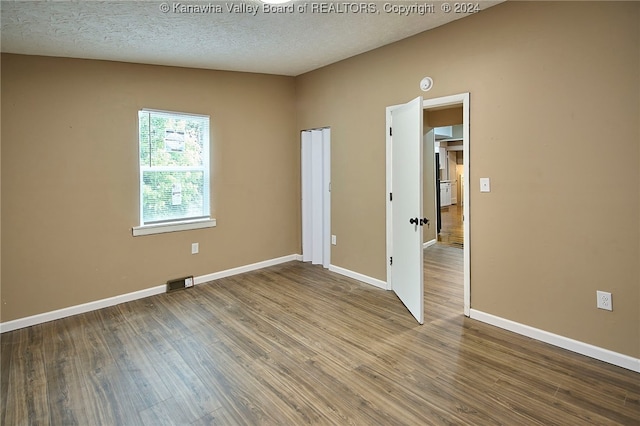 unfurnished room with lofted ceiling, a textured ceiling, and hardwood / wood-style floors