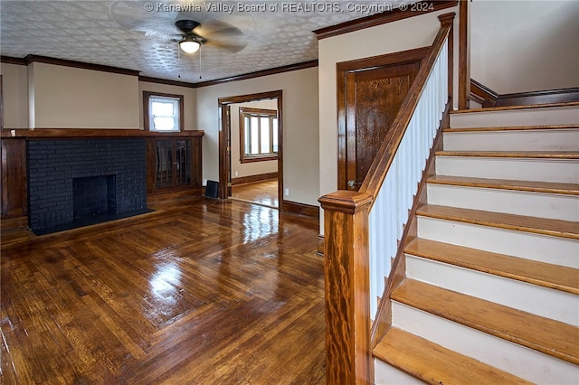 interior space with ceiling fan, a brick fireplace, wood-type flooring, a textured ceiling, and crown molding