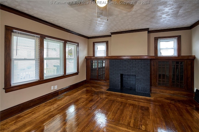 unfurnished living room with a brick fireplace, ornamental molding, a textured ceiling, and dark hardwood / wood-style flooring