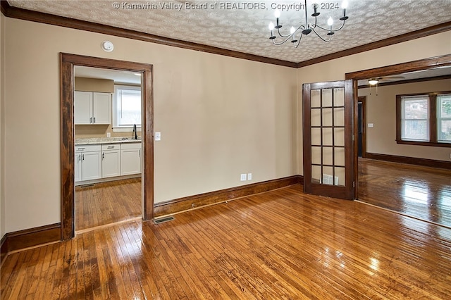 spare room featuring wood-type flooring, a wealth of natural light, and a textured ceiling