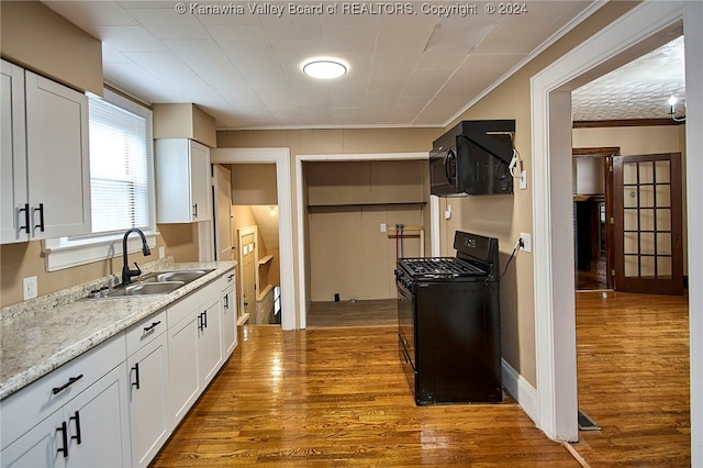 kitchen with black appliances, light hardwood / wood-style floors, and white cabinetry