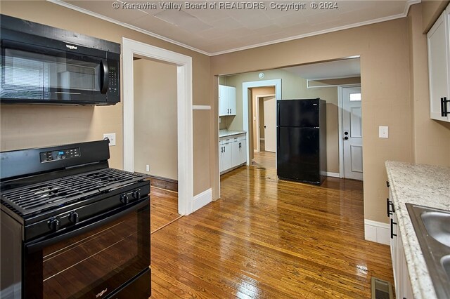 kitchen with white cabinets, light hardwood / wood-style flooring, crown molding, and black appliances