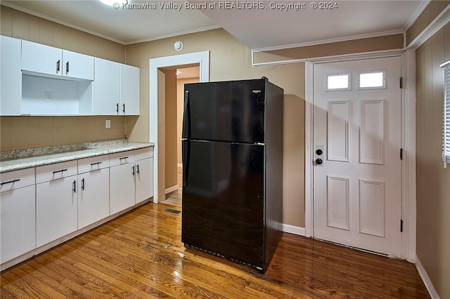 kitchen featuring ornamental molding, light hardwood / wood-style floors, black refrigerator, and white cabinetry