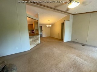 unfurnished living room featuring light carpet, a chandelier, and crown molding