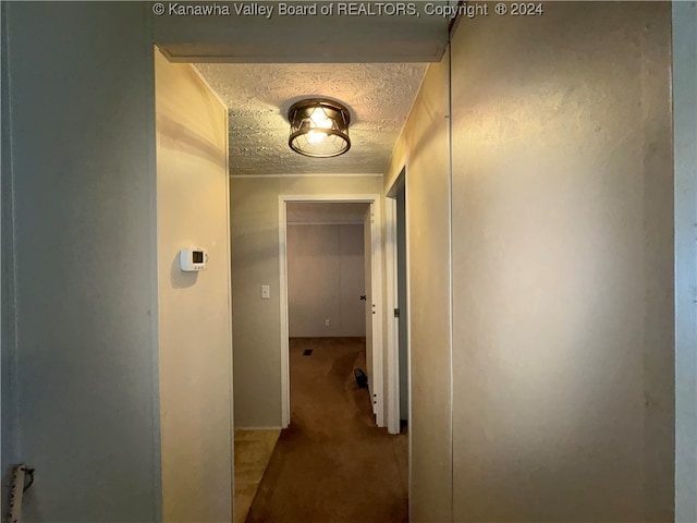 corridor with a textured ceiling and carpet flooring