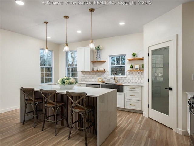 kitchen featuring pendant lighting, sink, a breakfast bar area, white cabinets, and a kitchen island