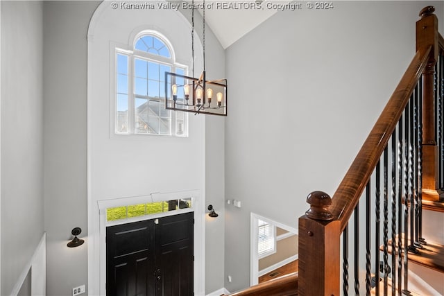 entrance foyer with wood-type flooring, vaulted ceiling, and an inviting chandelier