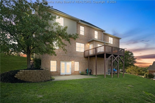 back of property at dusk featuring a lawn, brick siding, and a patio area