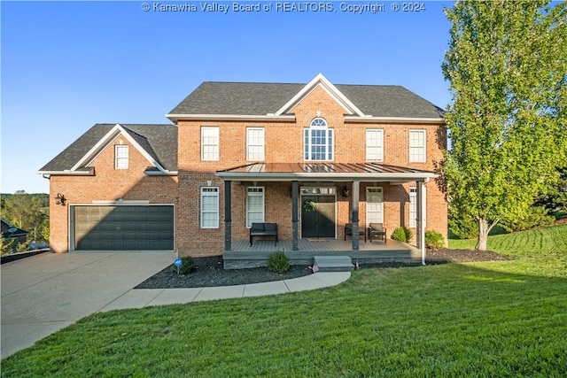 view of front of home with concrete driveway, a standing seam roof, covered porch, brick siding, and a front lawn