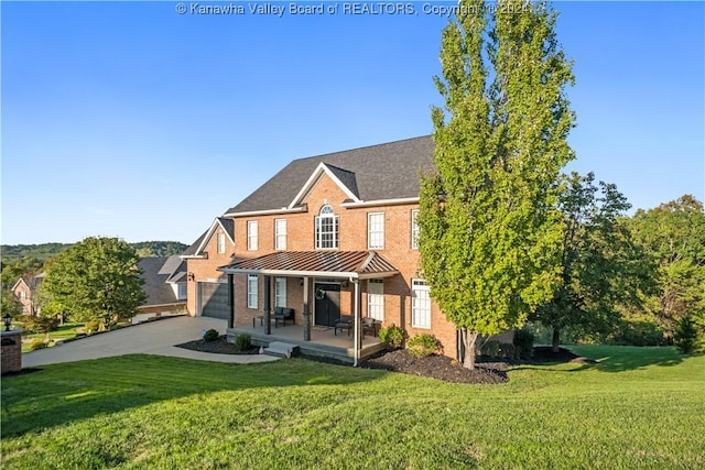 rear view of house with a porch, a standing seam roof, a yard, and brick siding