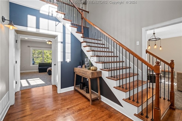 stairs with wood finished floors, a ceiling fan, visible vents, and baseboards