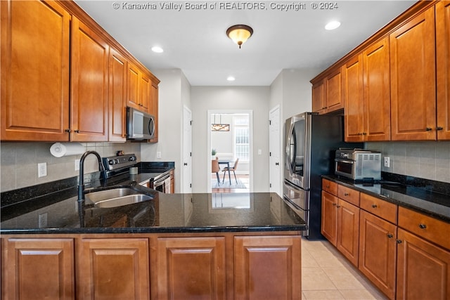 kitchen with decorative backsplash, dark stone countertops, appliances with stainless steel finishes, and sink