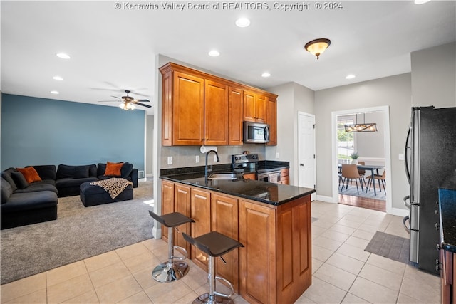 kitchen featuring dark stone counters, sink, kitchen peninsula, stainless steel appliances, and light tile patterned floors