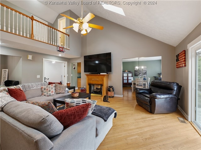 living room featuring a skylight, light hardwood / wood-style flooring, high vaulted ceiling, and ceiling fan