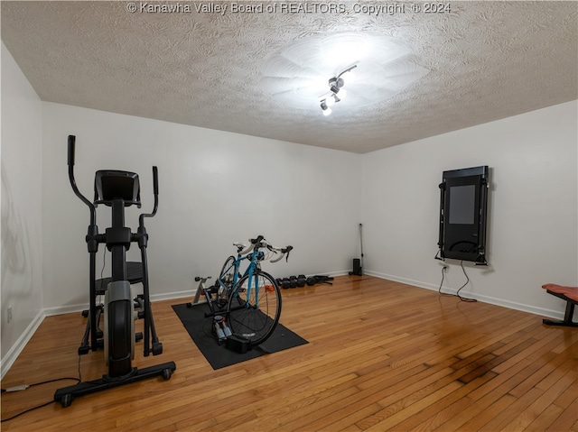 exercise area featuring a textured ceiling and wood-type flooring