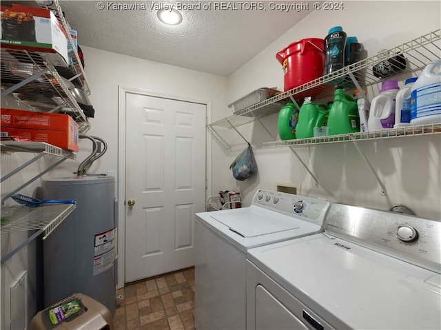 clothes washing area with water heater, washer and dryer, and a textured ceiling