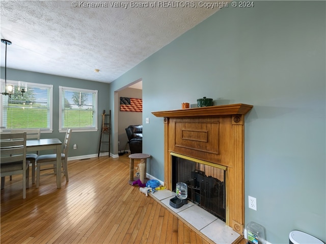 living room featuring light hardwood / wood-style flooring, a textured ceiling, and a chandelier