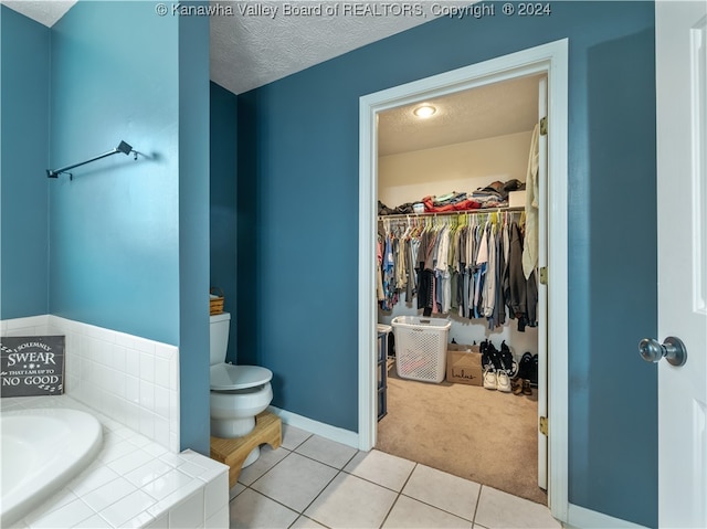 bathroom featuring toilet, a tub, a textured ceiling, and tile patterned flooring