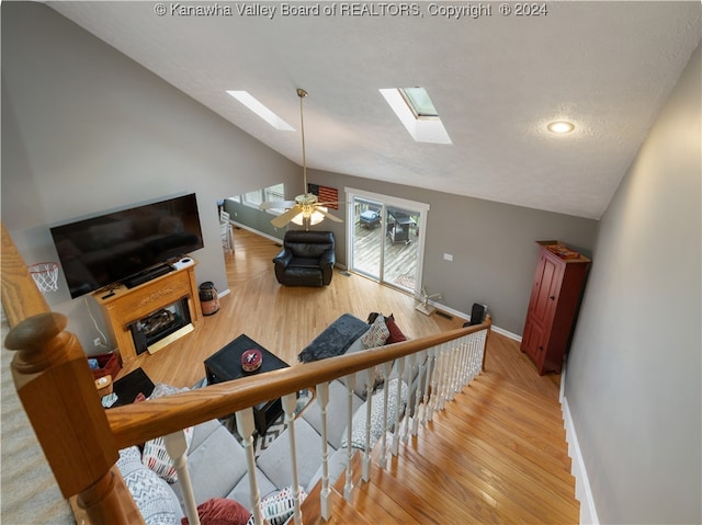 stairway featuring vaulted ceiling with skylight, hardwood / wood-style floors, a textured ceiling, and ceiling fan