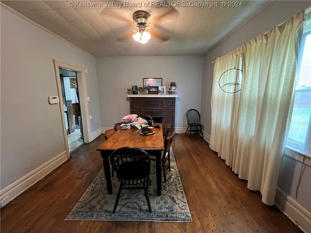 dining room with ceiling fan, a brick fireplace, and dark hardwood / wood-style flooring