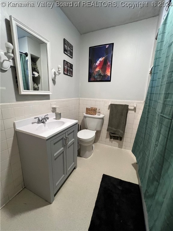 bathroom with tile walls, vanity, toilet, and a shower with curtain