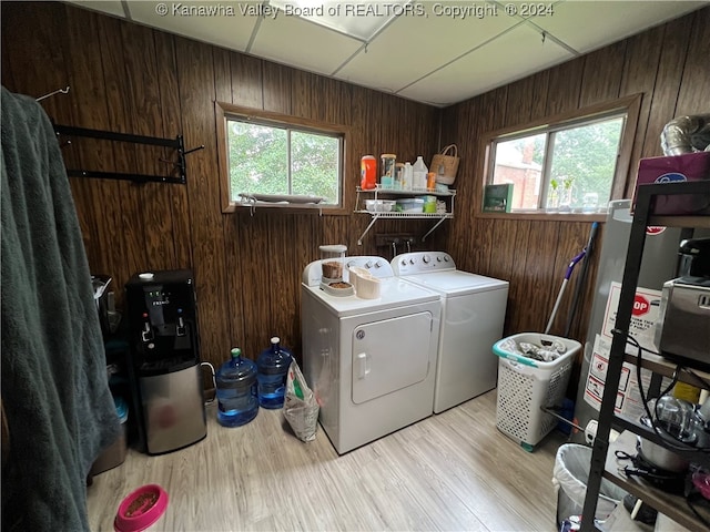 washroom featuring wooden walls, light hardwood / wood-style flooring, independent washer and dryer, and a healthy amount of sunlight