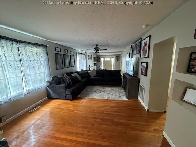 living room featuring ceiling fan, a textured ceiling, and hardwood / wood-style floors