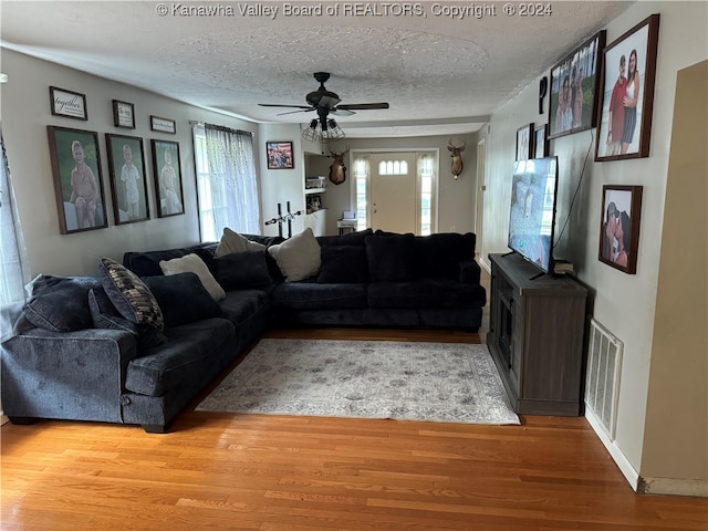 living room featuring a textured ceiling, light hardwood / wood-style floors, and ceiling fan