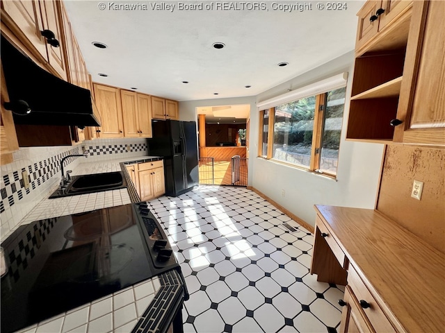 kitchen featuring light brown cabinets, stove, sink, tasteful backsplash, and black fridge with ice dispenser