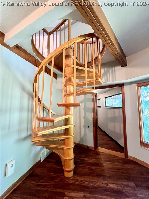 stairs with hardwood / wood-style floors and beam ceiling