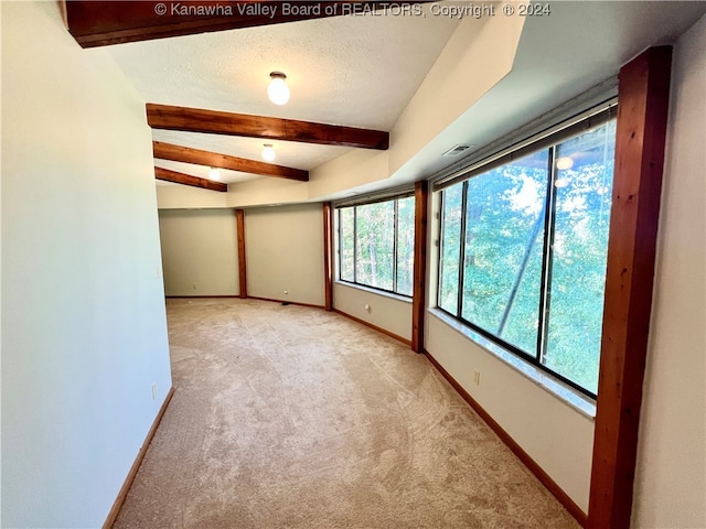 carpeted spare room with beam ceiling and a textured ceiling