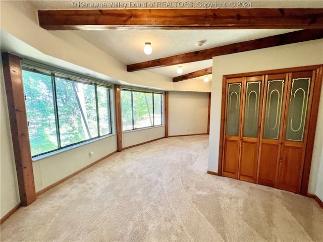 carpeted spare room featuring vaulted ceiling with beams