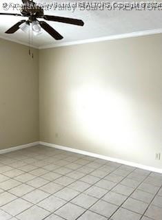 tiled empty room featuring ceiling fan and crown molding