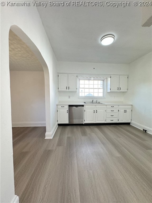 kitchen featuring light hardwood / wood-style flooring, sink, stainless steel dishwasher, white cabinets, and a textured ceiling