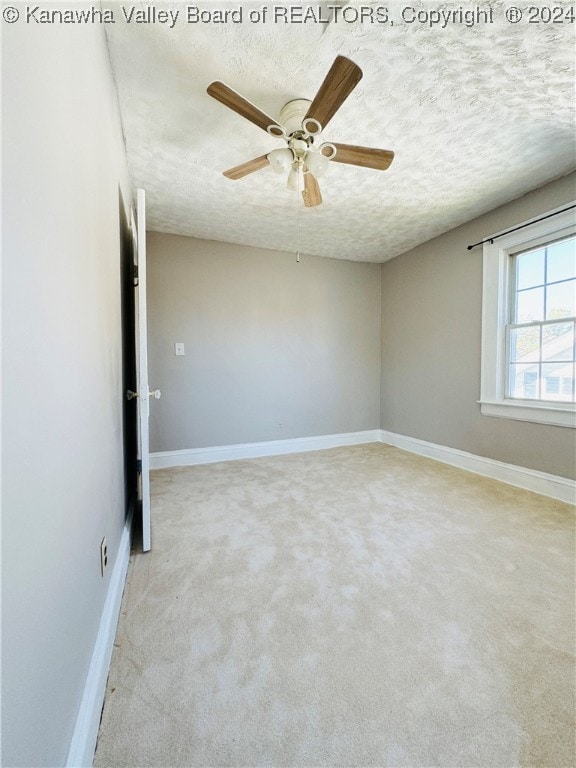 carpeted empty room featuring ceiling fan and a textured ceiling