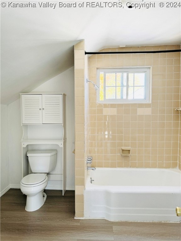 bathroom with tiled shower / bath, lofted ceiling, wood-type flooring, and toilet