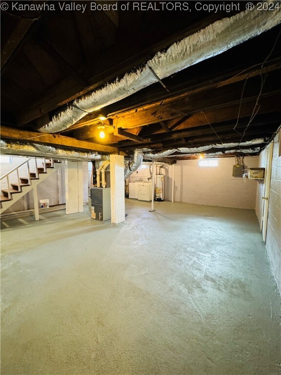 basement featuring water heater, heating unit, and washer and clothes dryer