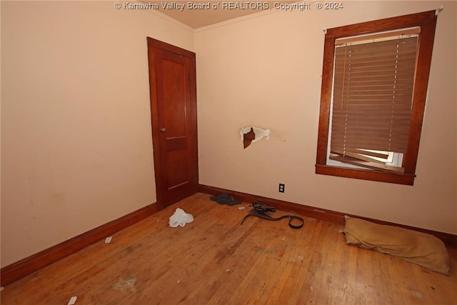 empty room with wood-type flooring and crown molding