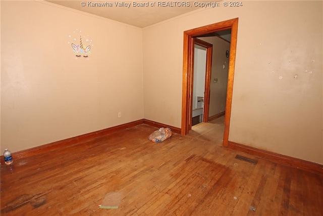 empty room with wood-type flooring and crown molding