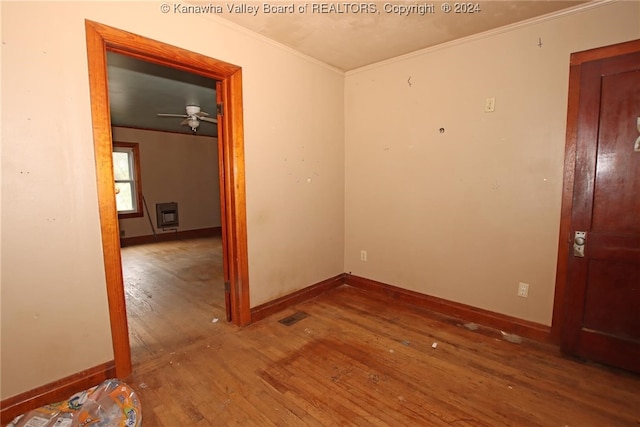 unfurnished room with heating unit, wood-type flooring, ornamental molding, and ceiling fan