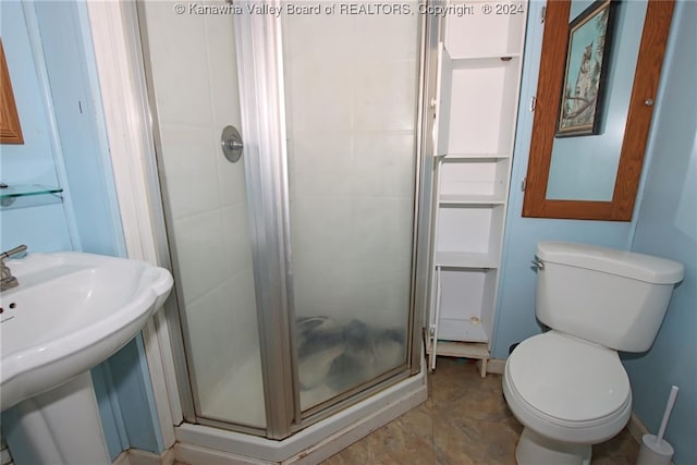 bathroom featuring a shower with shower door and toilet