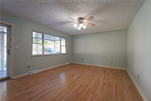 empty room featuring ceiling fan, a textured ceiling, and light hardwood / wood-style flooring