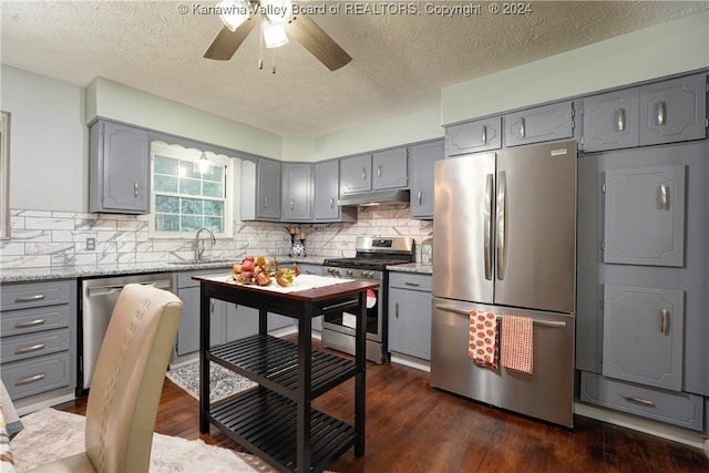 kitchen featuring dark hardwood / wood-style flooring, stainless steel appliances, a textured ceiling, ceiling fan, and sink